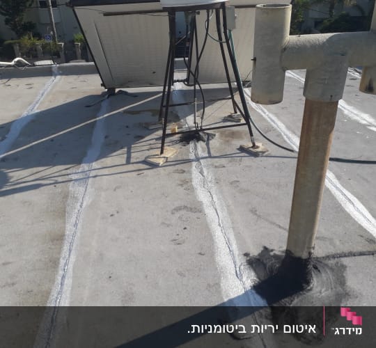 איטום גג עם חומר שחור סביב צינור